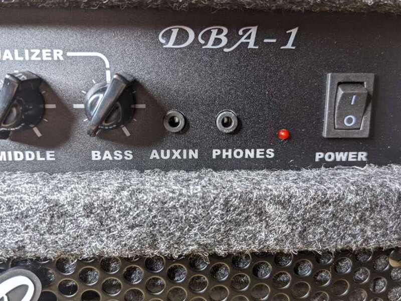 The auxiliary input, headphone output, red power light, and rocker power switch sit on the right side of the panel.