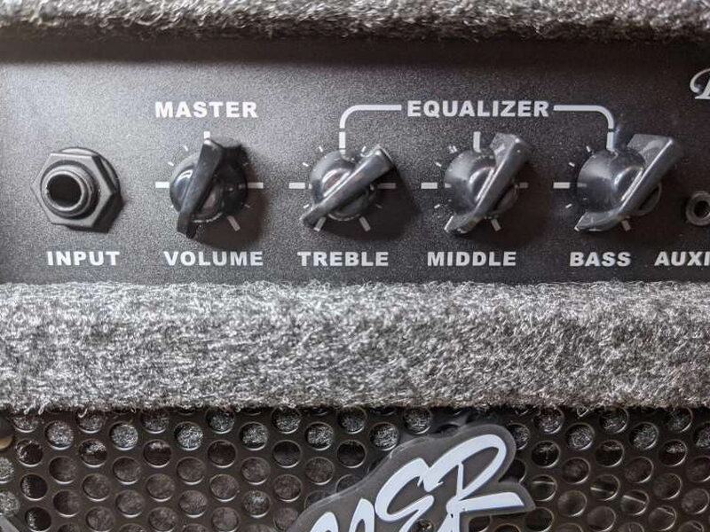 The 1/4 inch input and EQ knobs are clearly labeled on the recessed control panel.