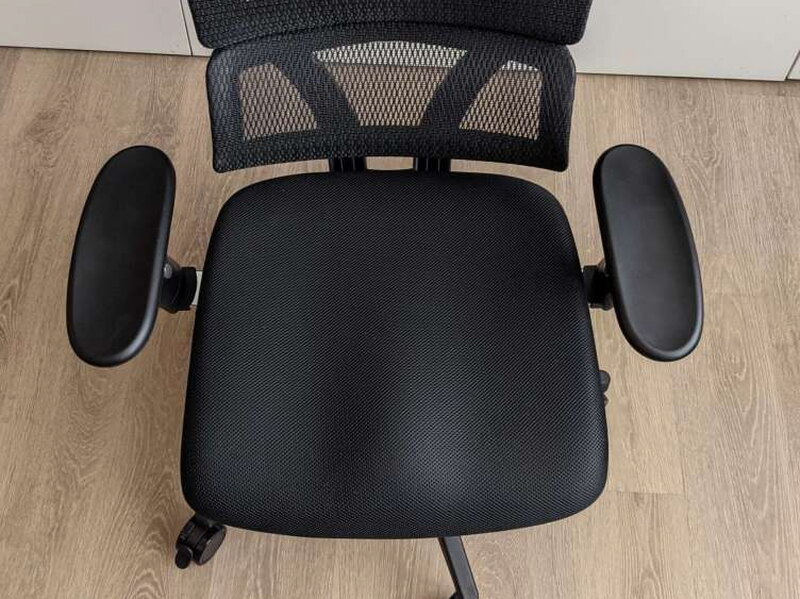 Looking straight down at the seat cushion, tight mesh weave, armrests on either side.