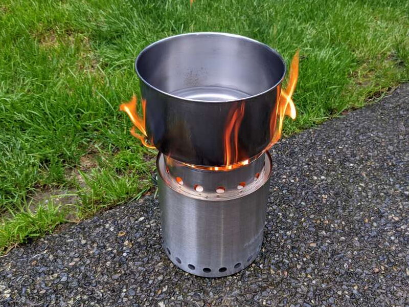 A pot balanced on the cooking ring’s tabs, flames licking up the sides.