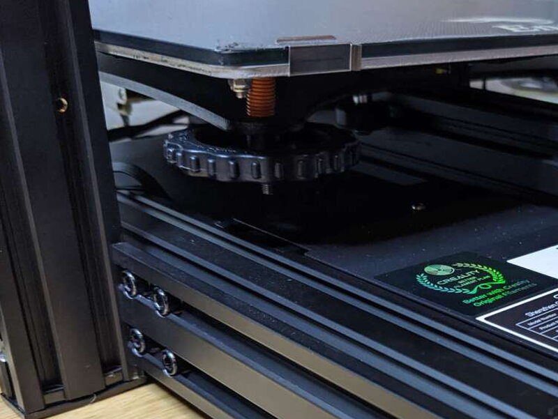 A large manual bed leveling knob sits under each corner of the build plate.