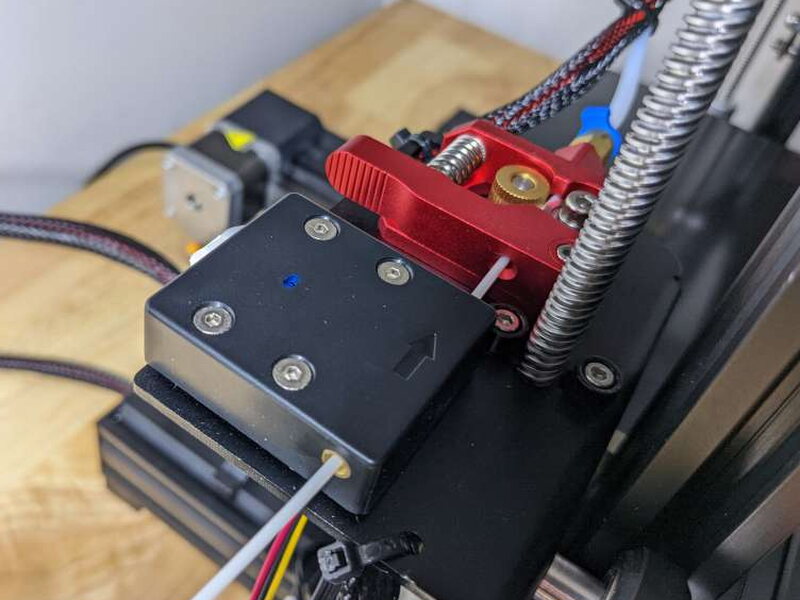 The filament runout detector is mounted beside the extruder path.
