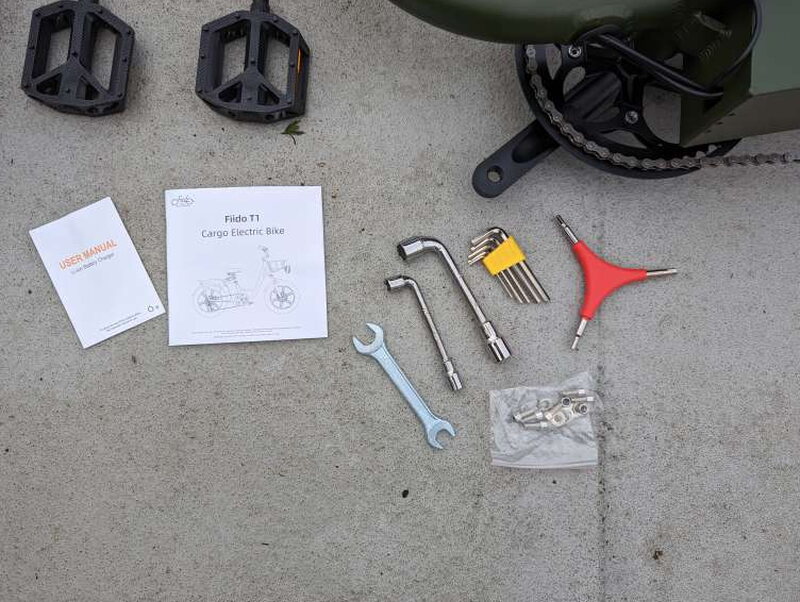 The included manual, pedals, tools, keys, charger, and small parts used during assembly.