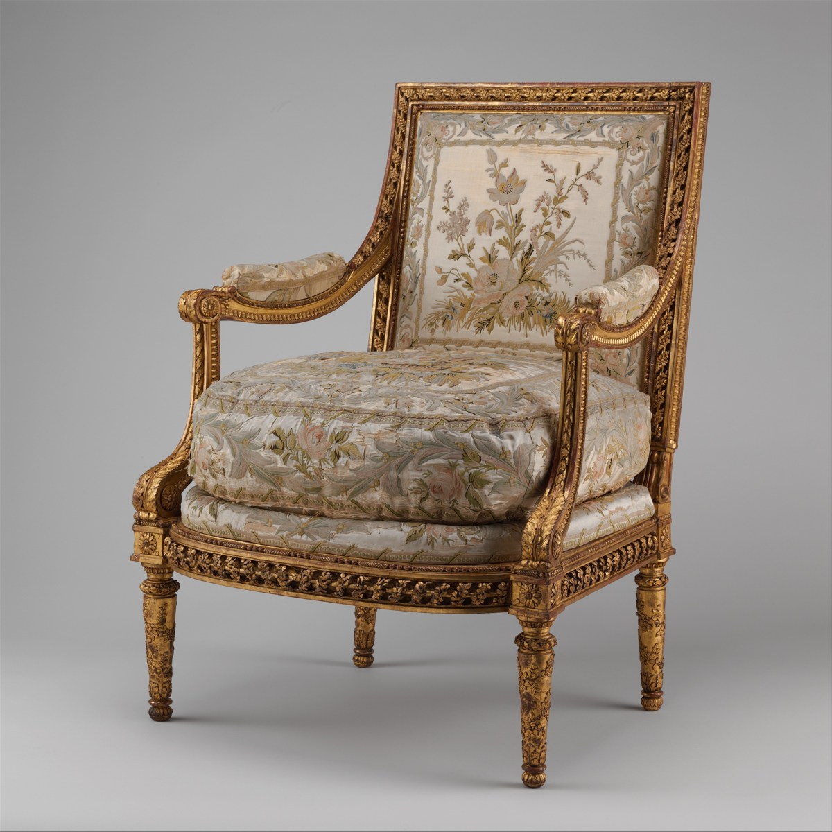 A carved and gilded French armchair with floral upholstery.