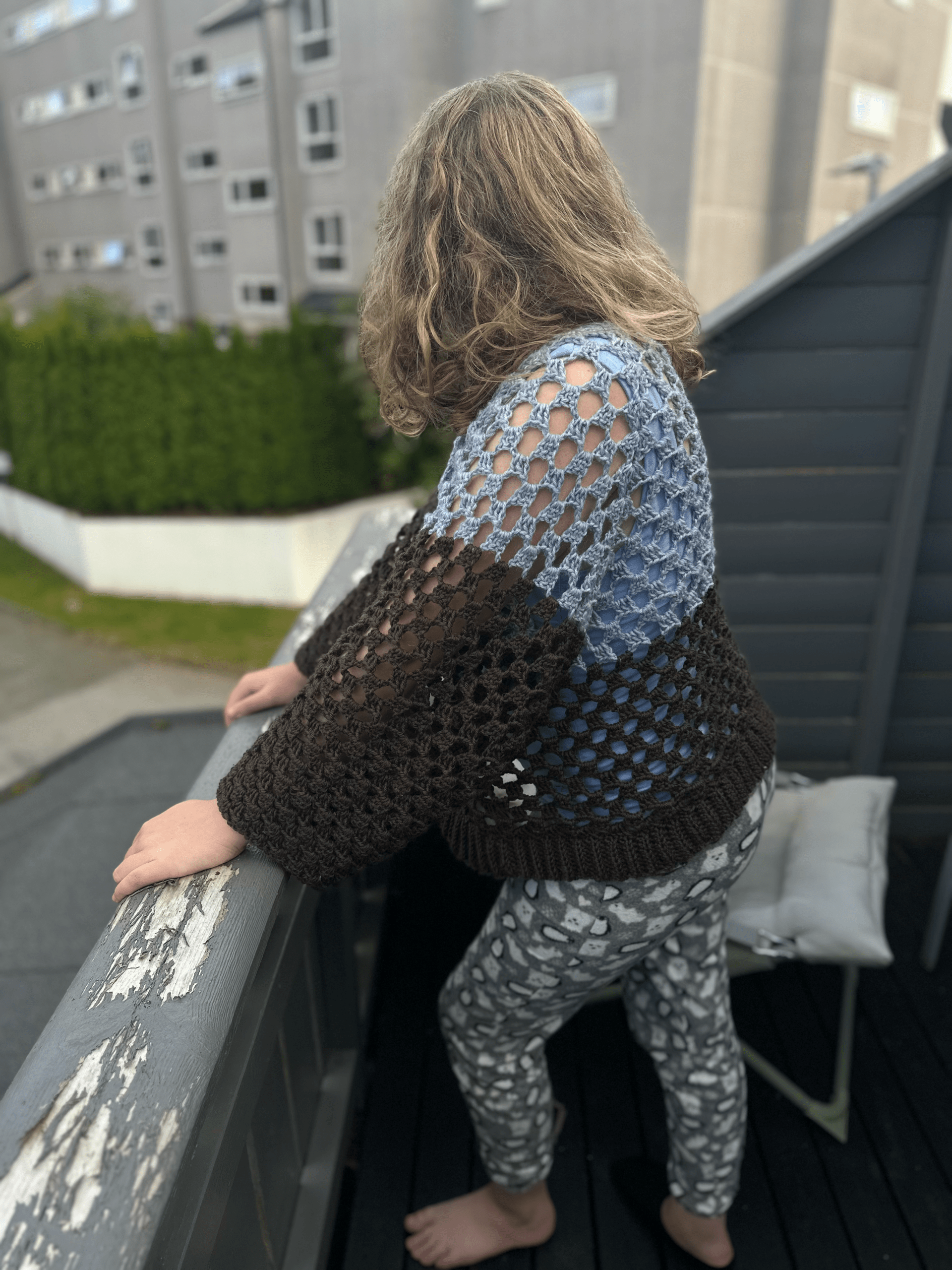 Picture of a girl wearing a crochet sweater. The sweater is light blue on top and dark brown at the bottom and the arms.