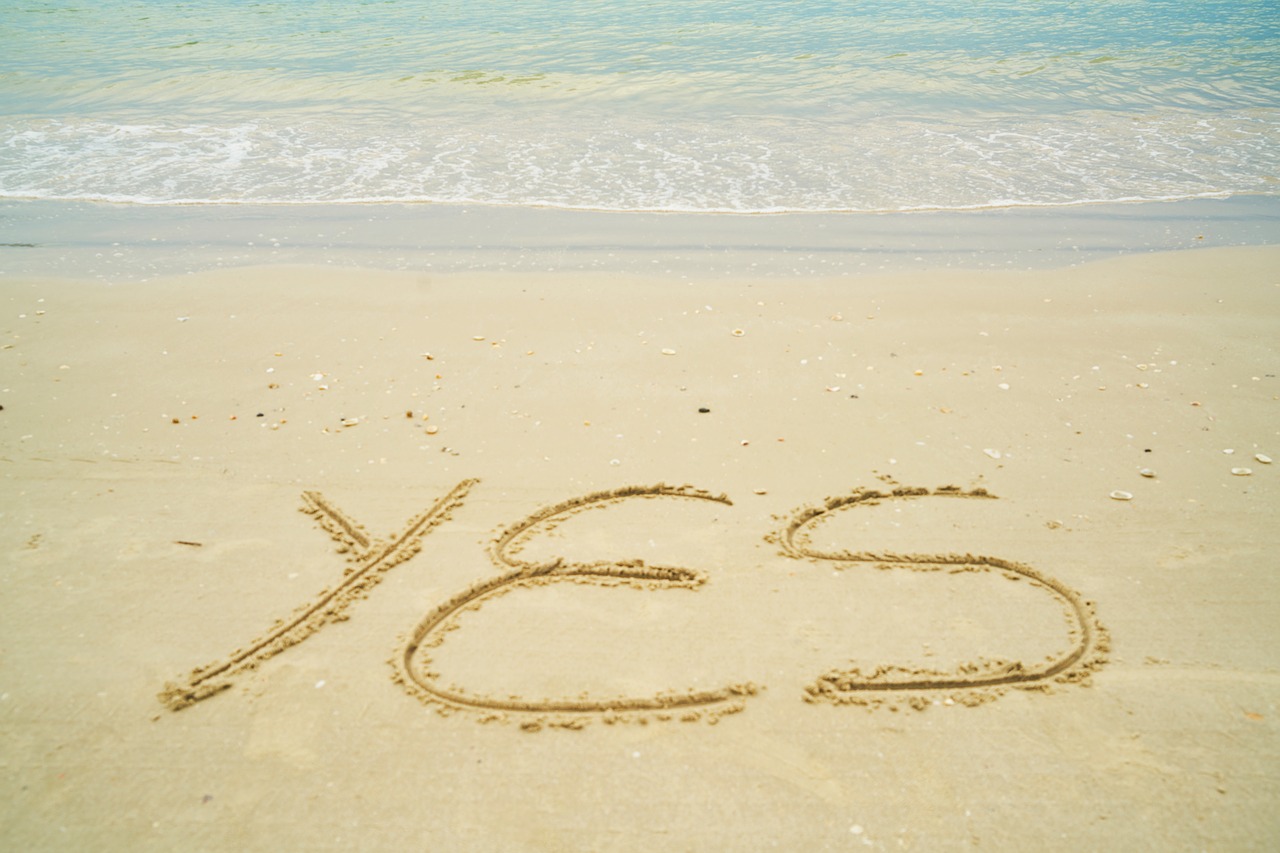 YES written in sand on a beach.