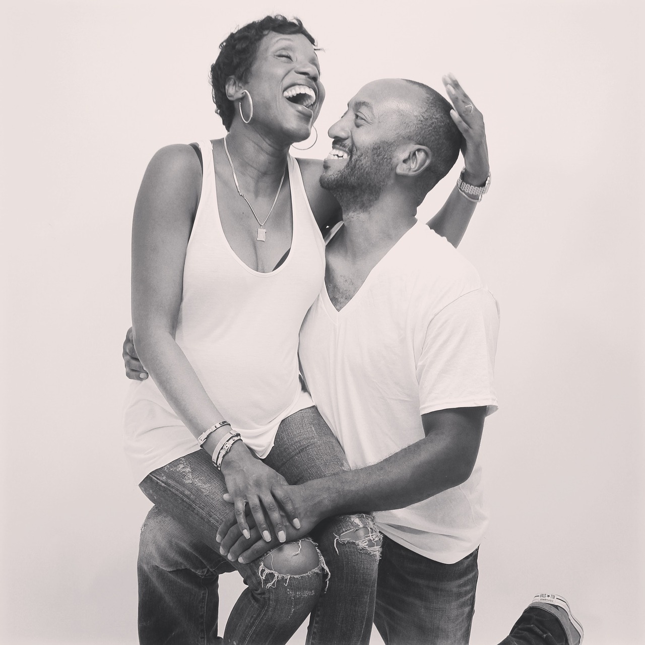 Black and white picture of a black woman sitting on a black man's knee. Both of them look joyful.
