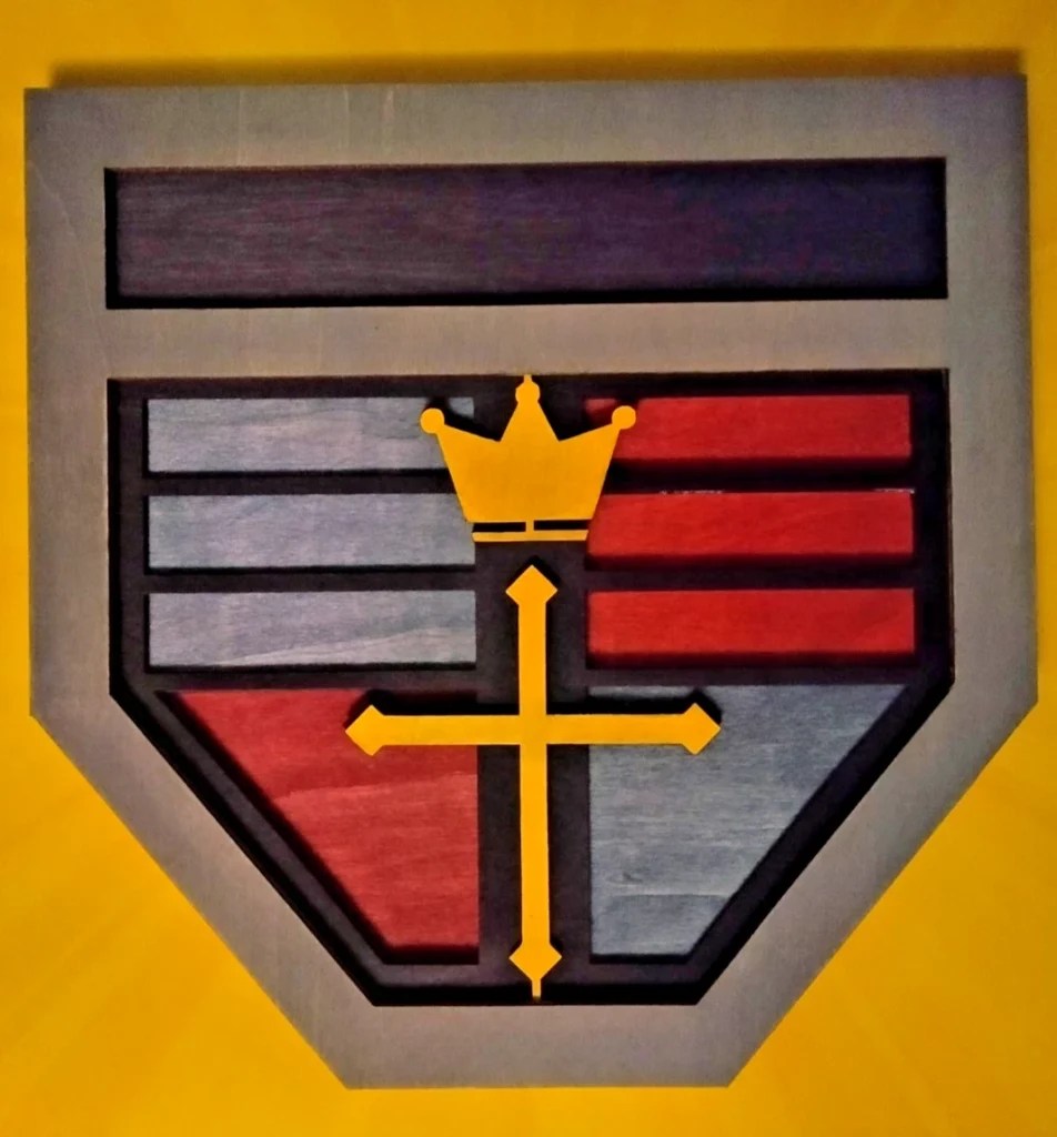 A multilayer representation of the Voltron or GoLion crest, featuring a shield design with blue, red, and gray sections, and a yellow crown above a central cross symbol.