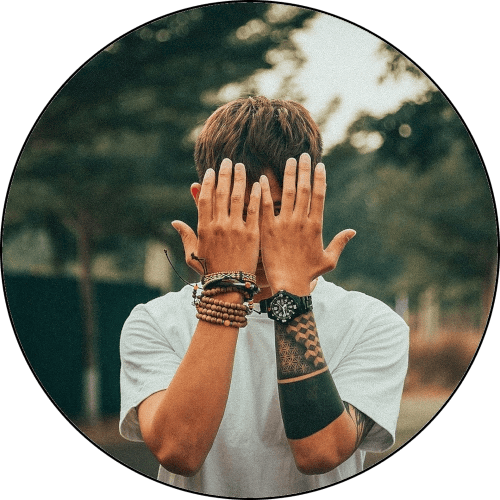 foto di un ragazzo che si copre il volto con le mani per timidezza