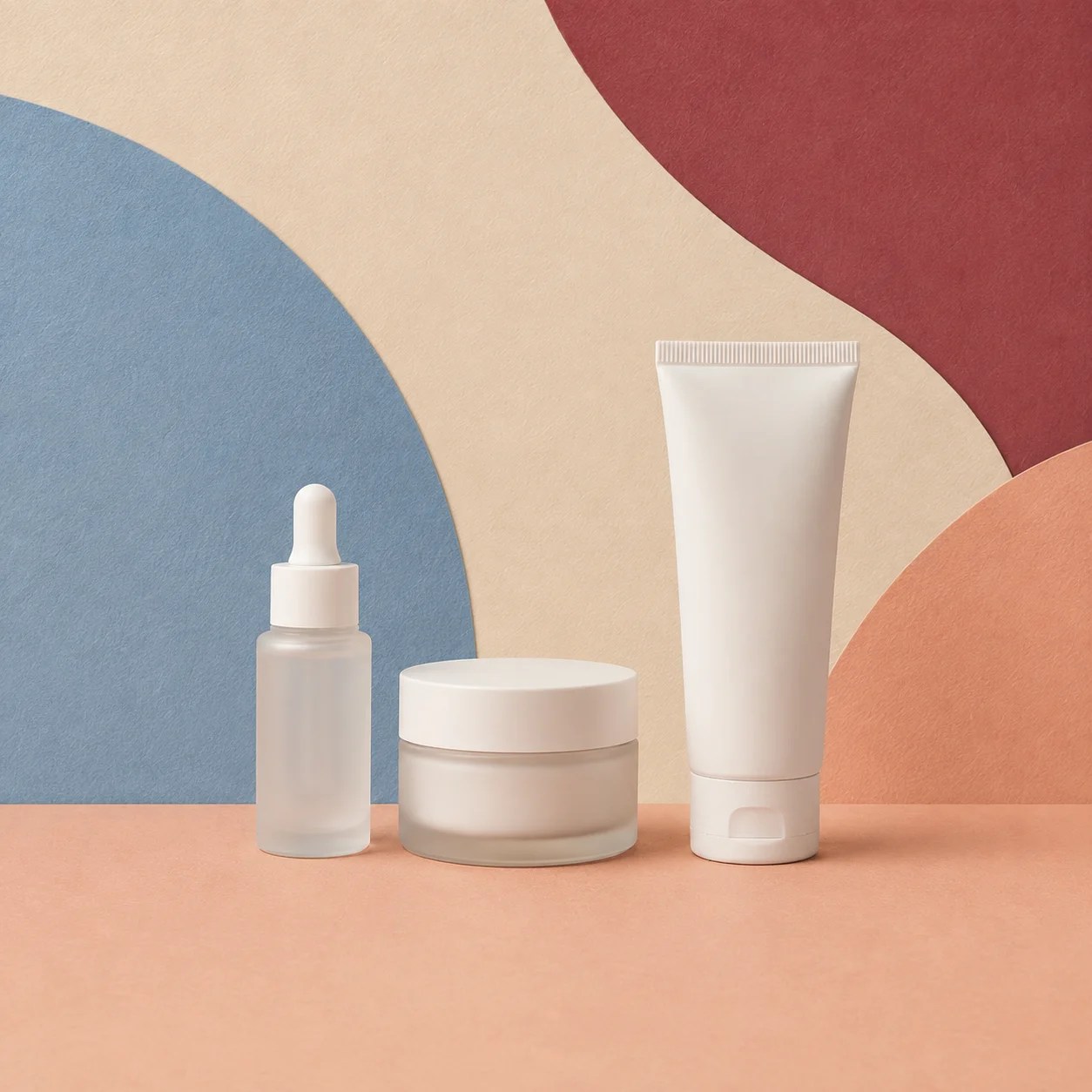 Serum, moisturizer, and sunscreen arranged on textured paper blocks