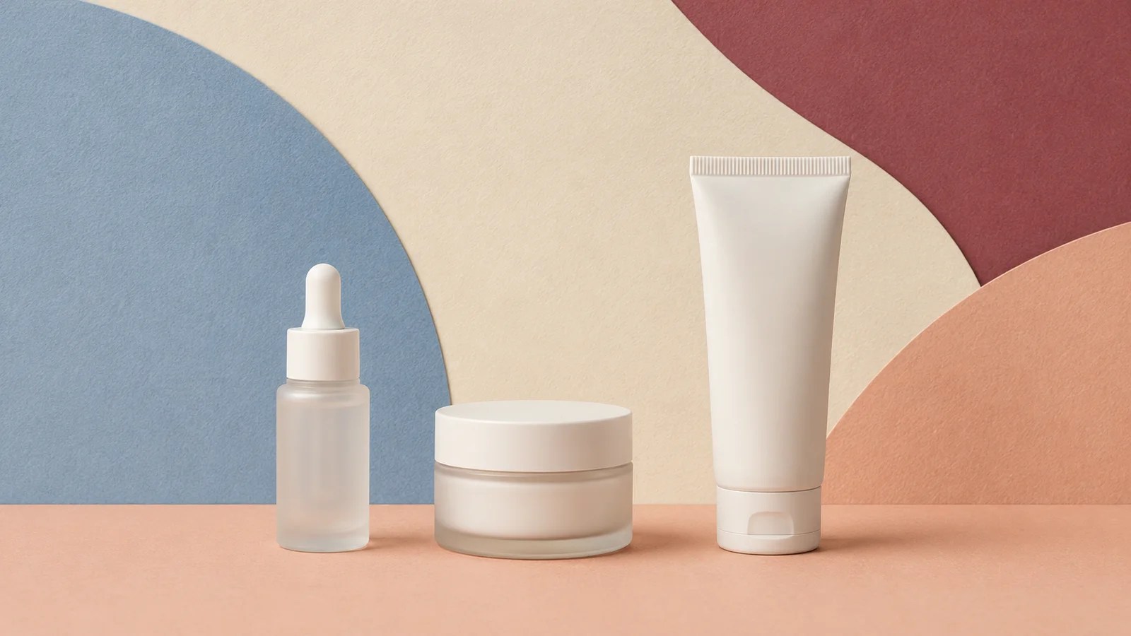 Serum, moisturizer, and sunscreen arranged on textured paper blocks