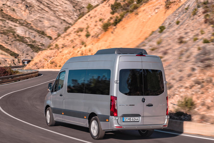 Silver Mercedes-Benz Sprinter van driving on a winding road with rocky hills in the background