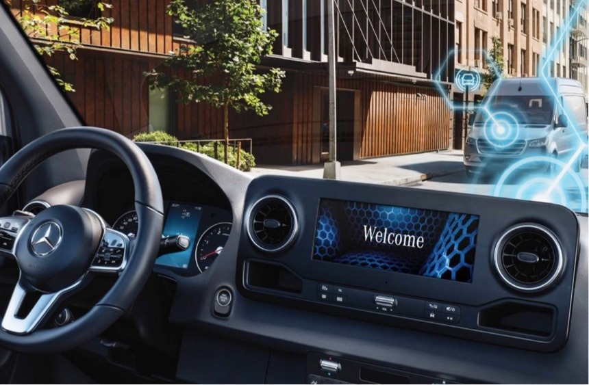 Mercedes-Benz van interior showing dashboard infotainment screen displaying "Welcome," with digital connectivity graphics overlaid on an urban street scene