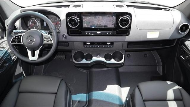 Interior view of a Mercedes-Benz van cabin showing the steering wheel, touchscreen infotainment system, dashboard, and front seats