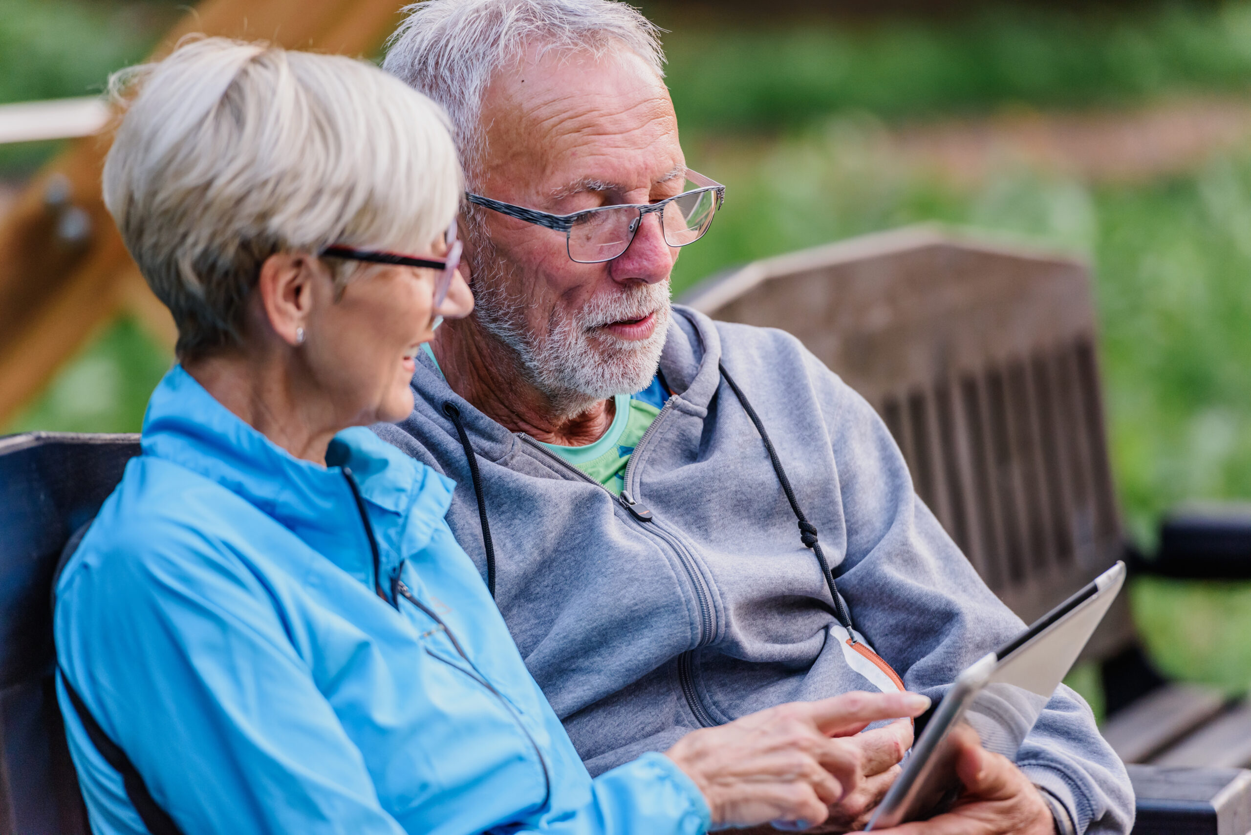 Older couple sitting outside looking at phone together