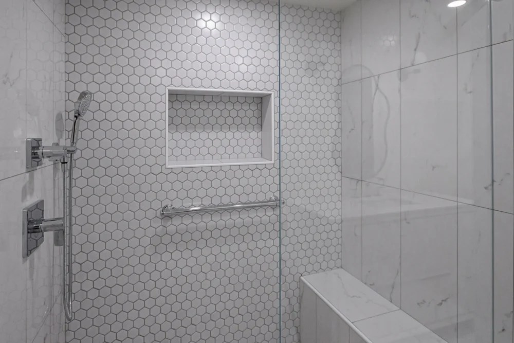 Hex tile shower with recessed niche and grab bar in a Lexington MA bathroom renovation