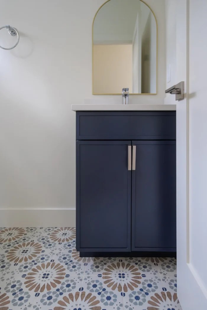 Powder room with navy vanity and patterned cement tile floor in Lexington MA