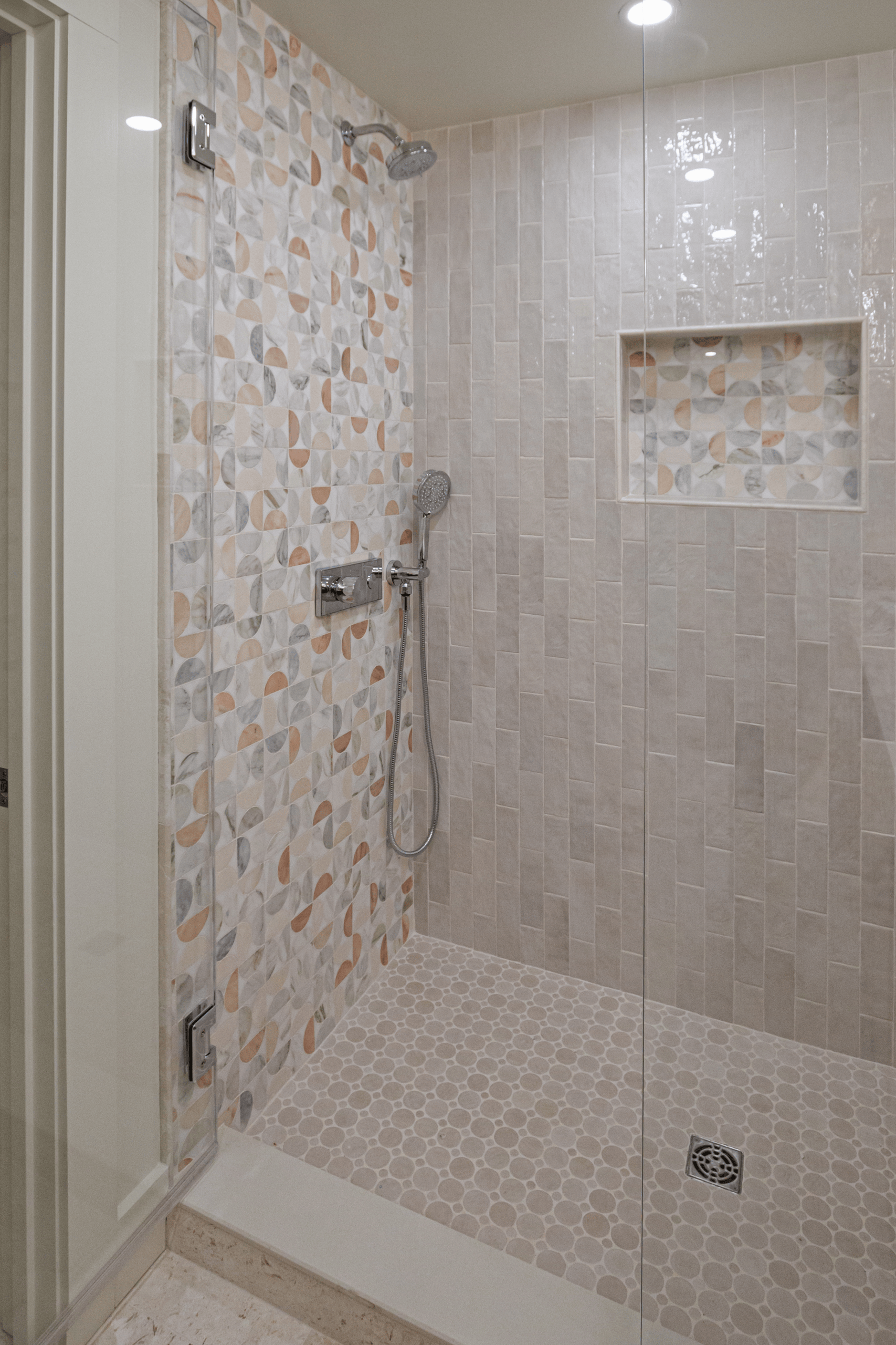 Marble mosaic accent wall and pebble floor shower in a Lexington MA bathroom renovation