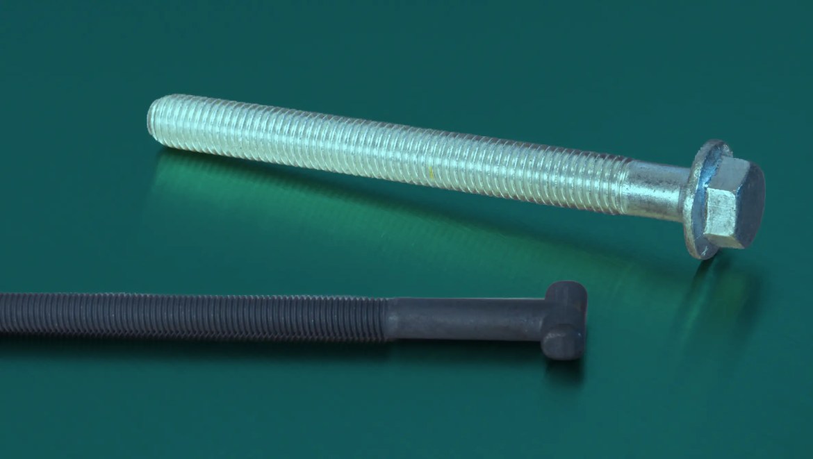 Metal bolt with external threads and hex head on a green surface, viewed from the side