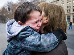 crying boy clutches to mother who holds him close- maybe they have to separate