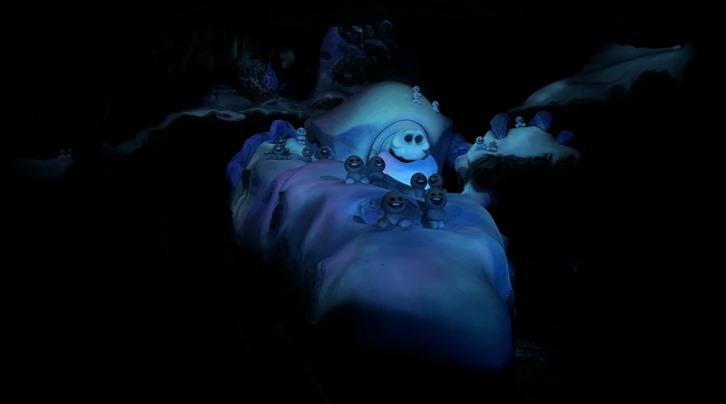 A scene from the Frozen Ever After ride featuring animated snow creatures in a snowy landscape under dim lighting.
