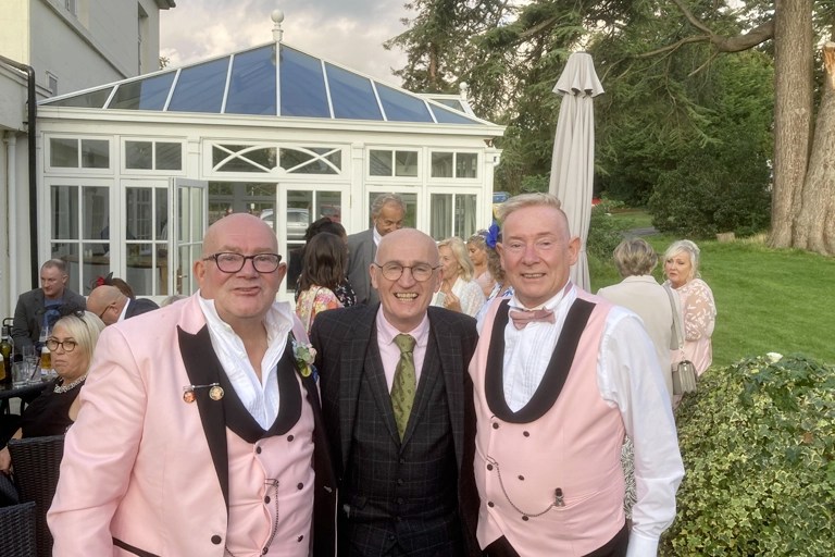 chester close up magician at same sex wedding. magician posing with two husbands.