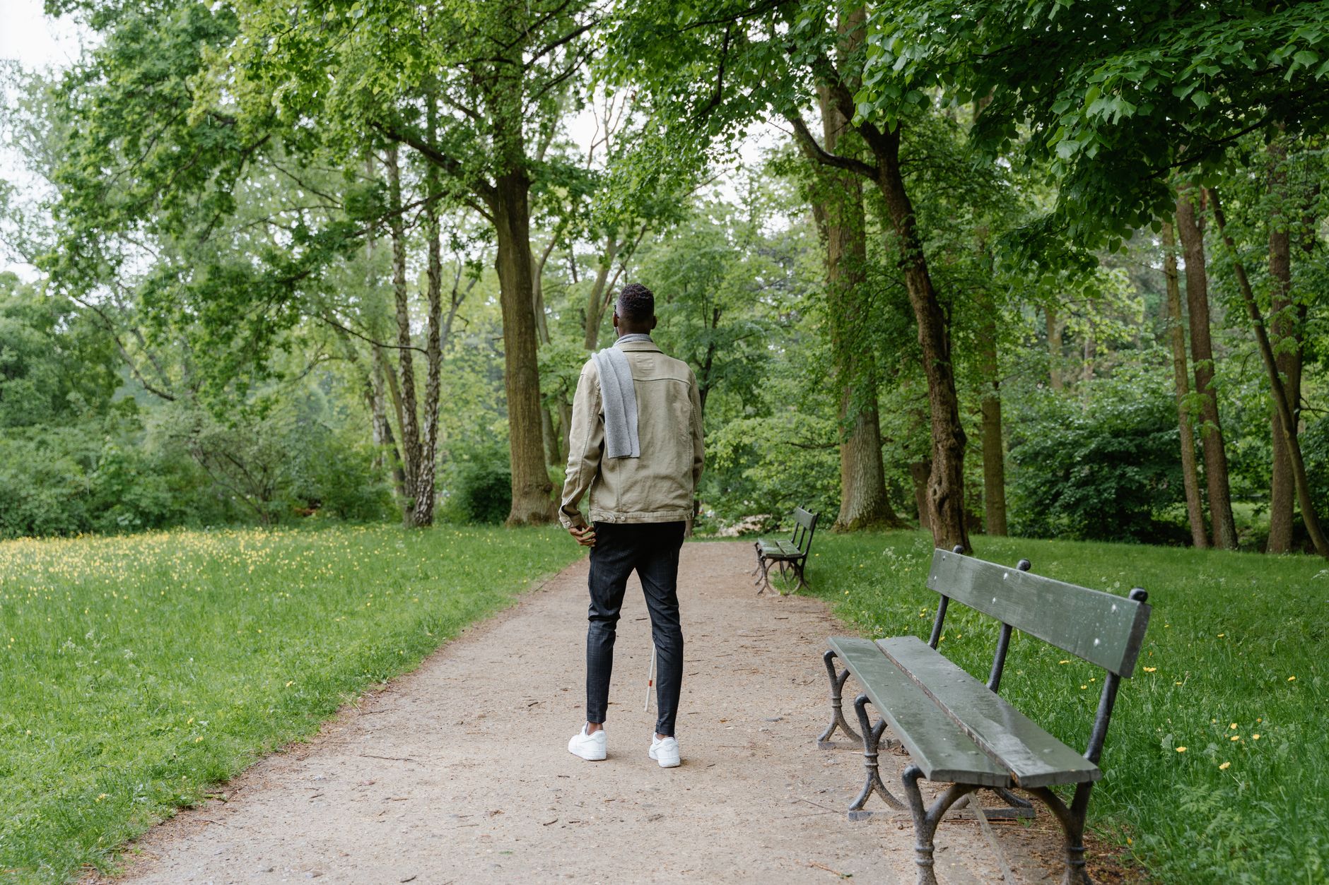blind man with a white cane walking in the park