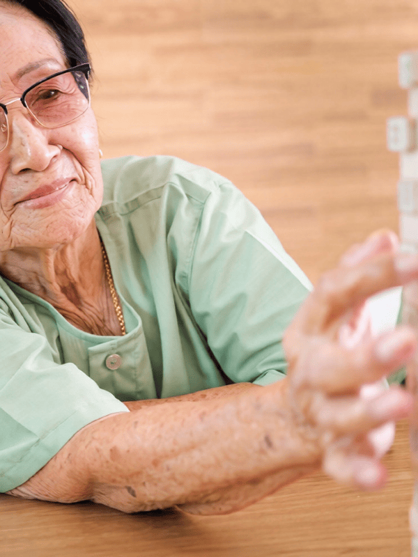 Senior woman playing jenga in a Make More Cognitive Wellbeing Activities session.