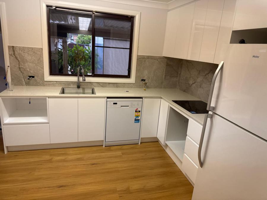 White kitchen cabinetry and stone-look splashback during installation