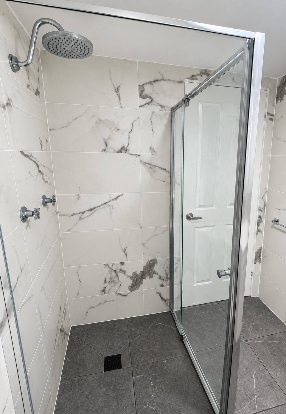 Completed framed glass shower enclosure with marble-look wall tiles