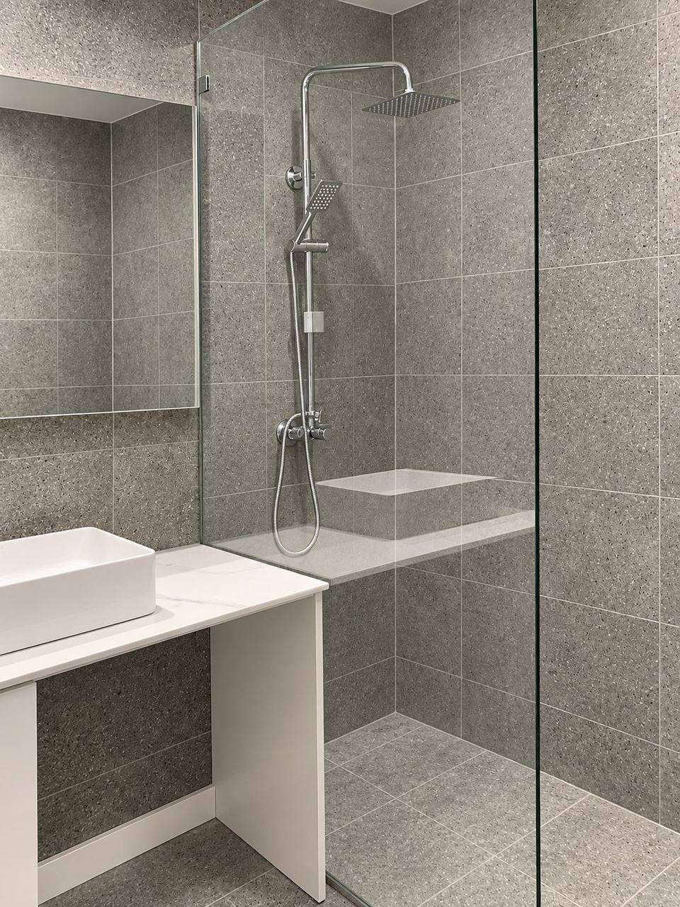 Completed grey tiled bathroom with frameless shower and vessel basin