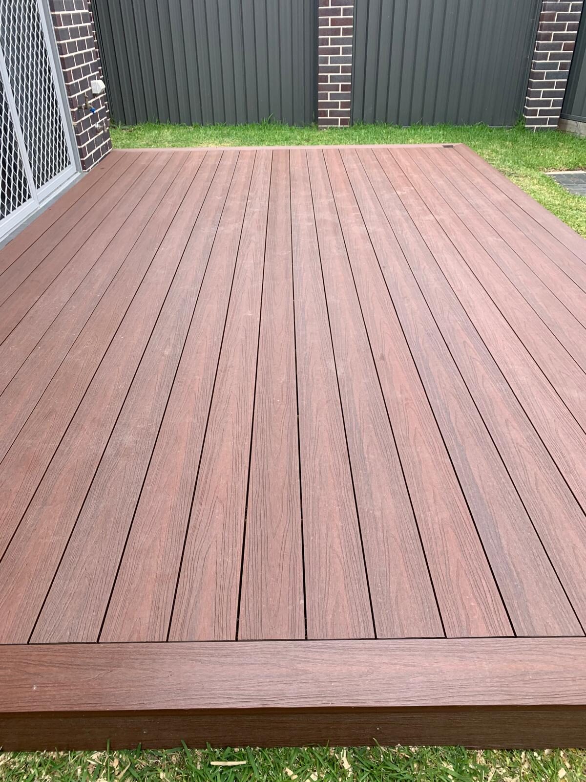 Completed low-maintenance composite deck beside a lawn