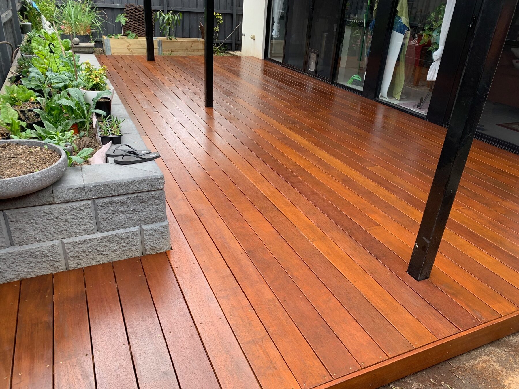 Completed wide Merbau entertaining deck beside garden beds
