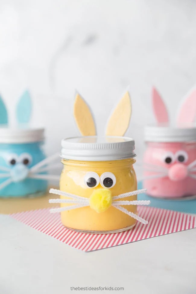 Bunny slime sensory activity in small jars decorated with bunny ears, googly eyes, and pipe cleaner whiskers.