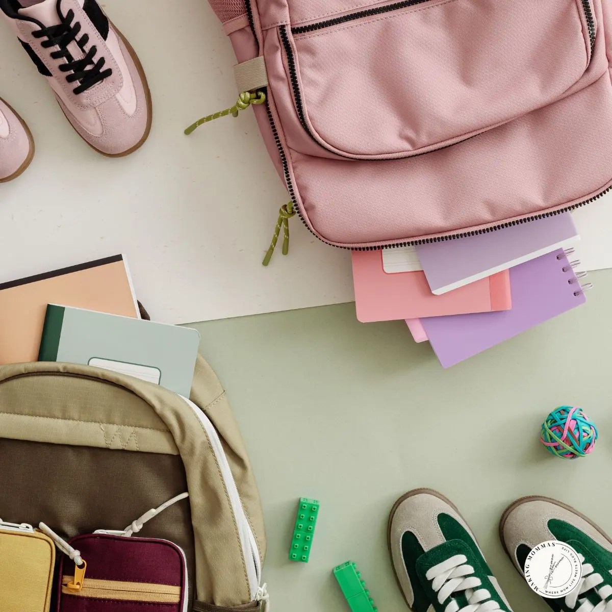 Flat lay of back-to-school essentials including pink and tan backpacks, notebooks, sneakers, and small school supplies on a light background.