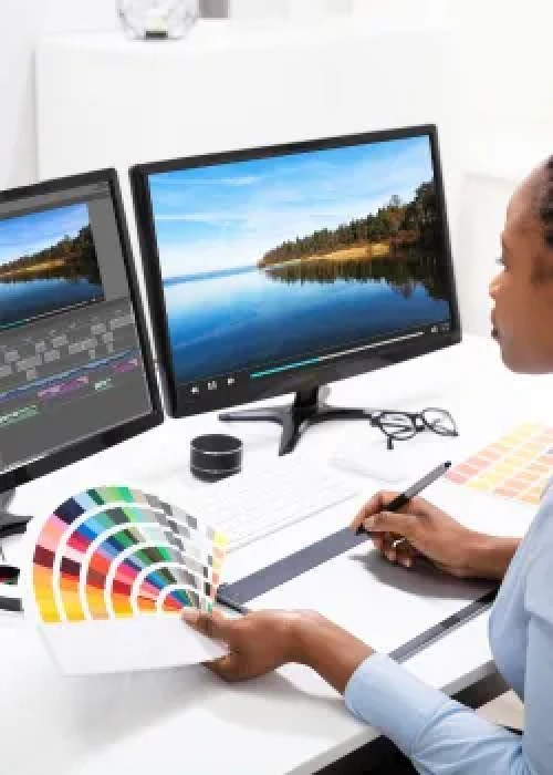 woman with color swatches looking at two computer screens