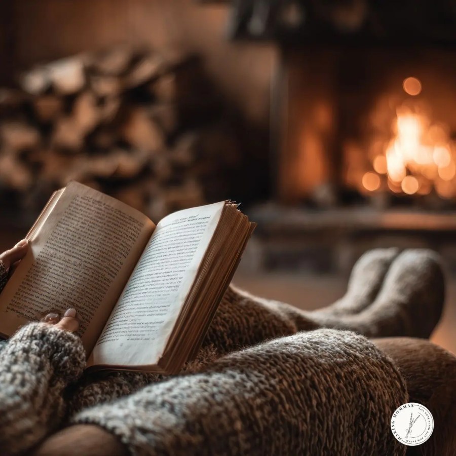 Cozy winter scene of a woman reading a book by the fireplace, wrapped in a knit blanket — a relaxing Christmas gift idea for stay-at-home moms who love quiet moments.