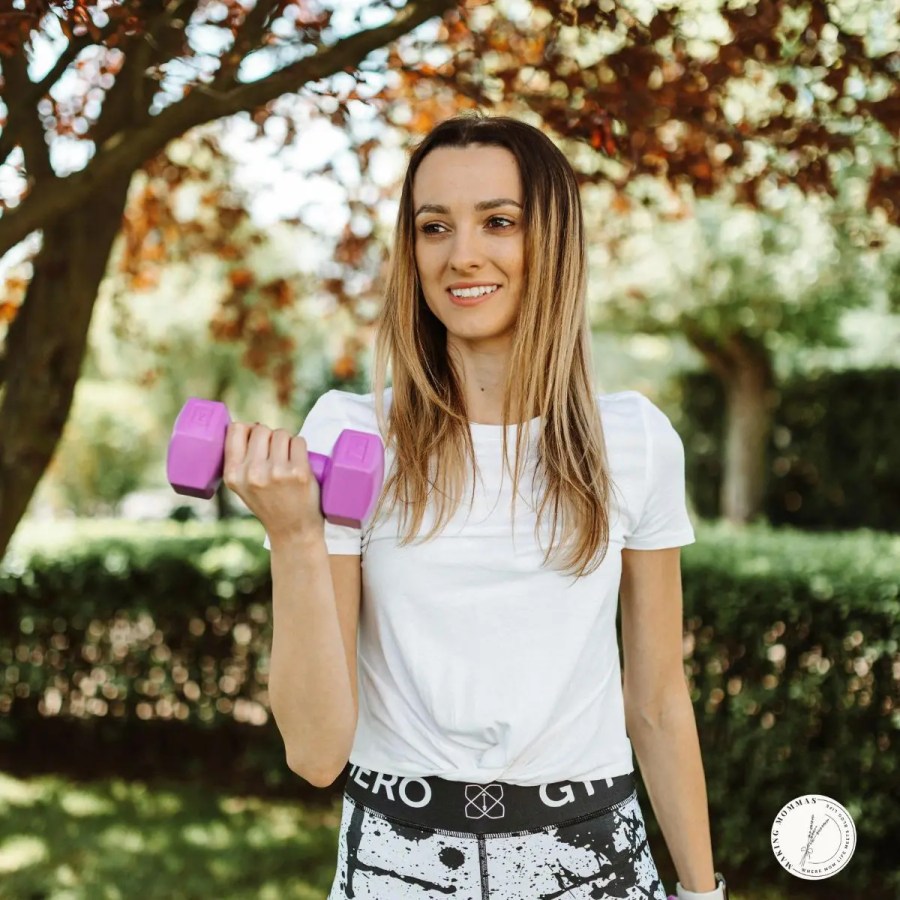Smiling woman lifting small purple dumbbells outdoors, representing a great Christmas gift idea for stay-at-home moms who enjoy simple home workouts.