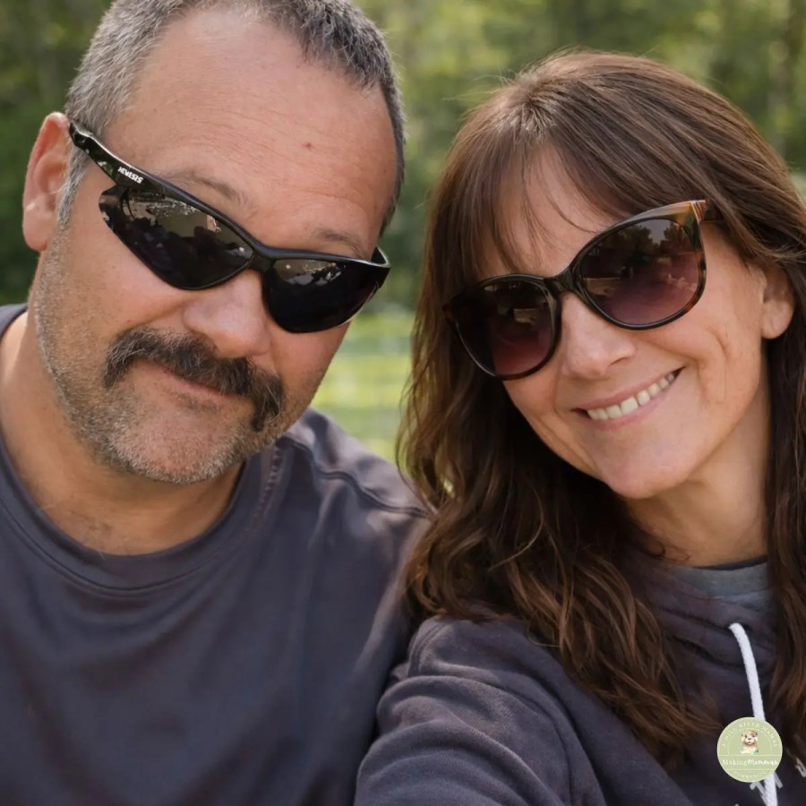 Couple wearing sunglasses smiling together outdoors, representing the family behind Hill River Homestead.