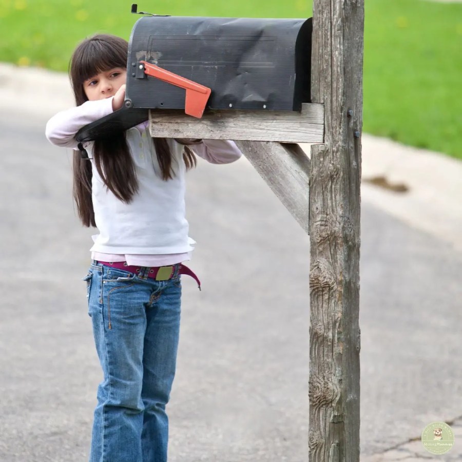 Young child standing by a roadside mailbox, reaching inside to check for mail.
