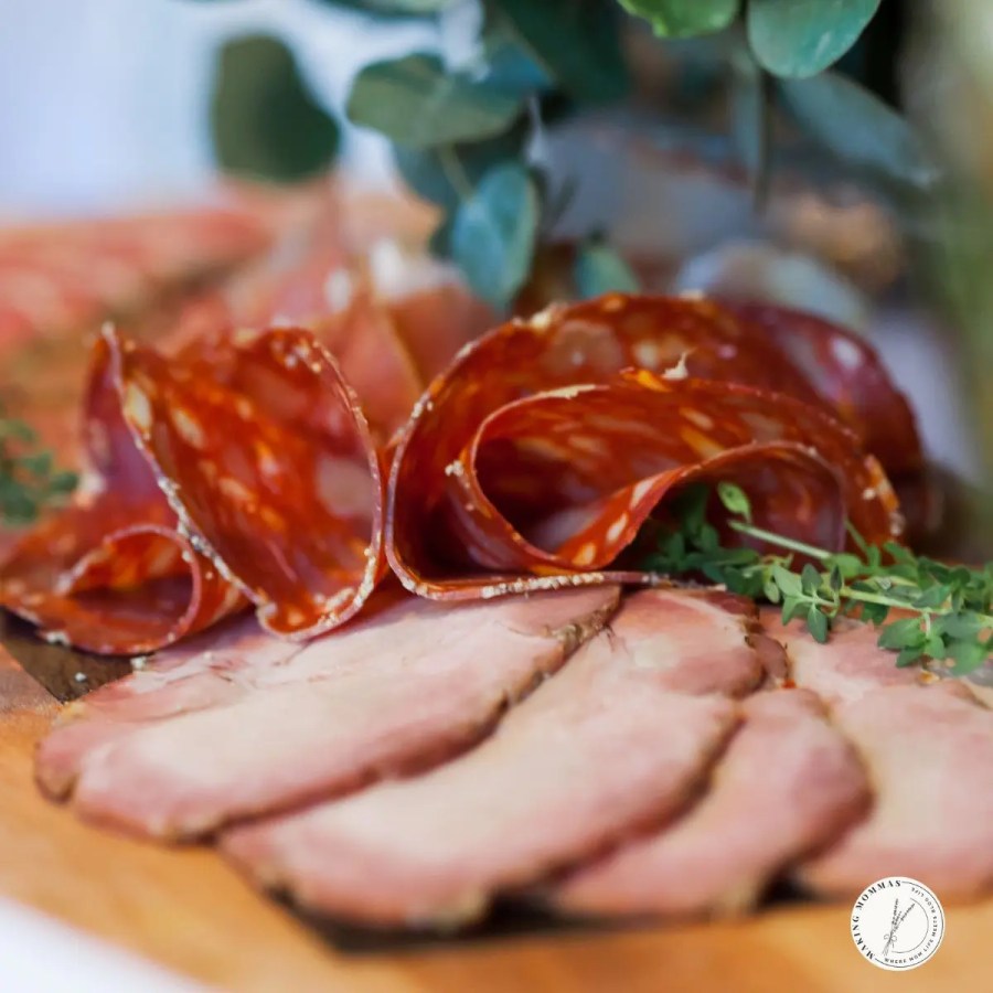 Close-up of thinly sliced cured meats on a wooden board, showcasing how a meat slicer can make homemade charcuterie and meal prep easy and professional-looking for busy moms.