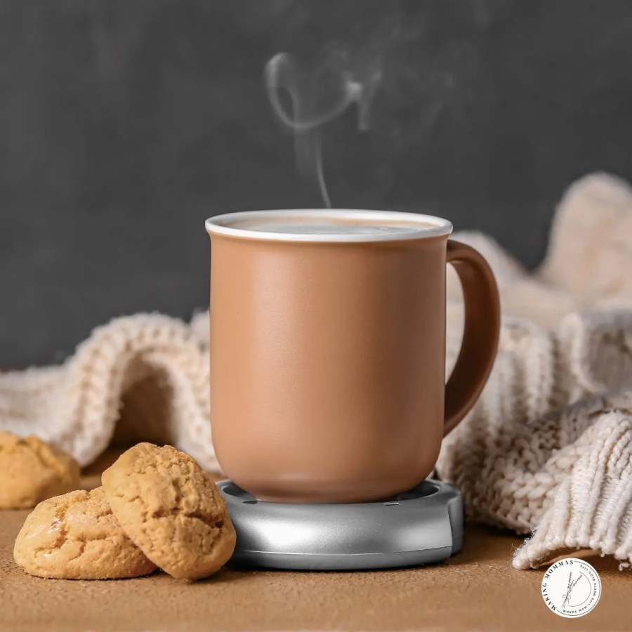 Warm ceramic mug sitting on a silver mug warmer beside cookies and a cozy knit blanket, perfect for keeping a mom’s coffee hot while she tackles her busy day.