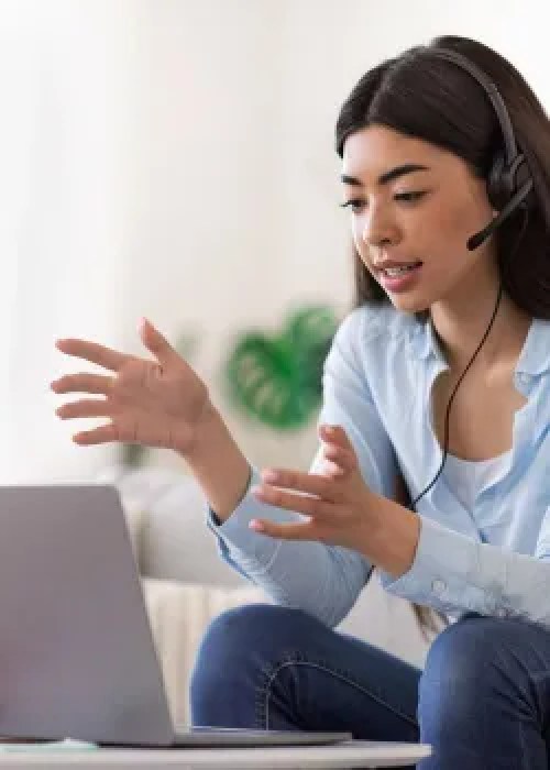woman with headset and microphone talking into computer screen