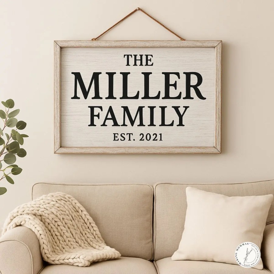 Alt text: A personalized farmhouse-style family name sign hanging on a beige wall above a cozy tan couch with a knit blanket and pillow, reading “The Miller Family, Est. 2021.”