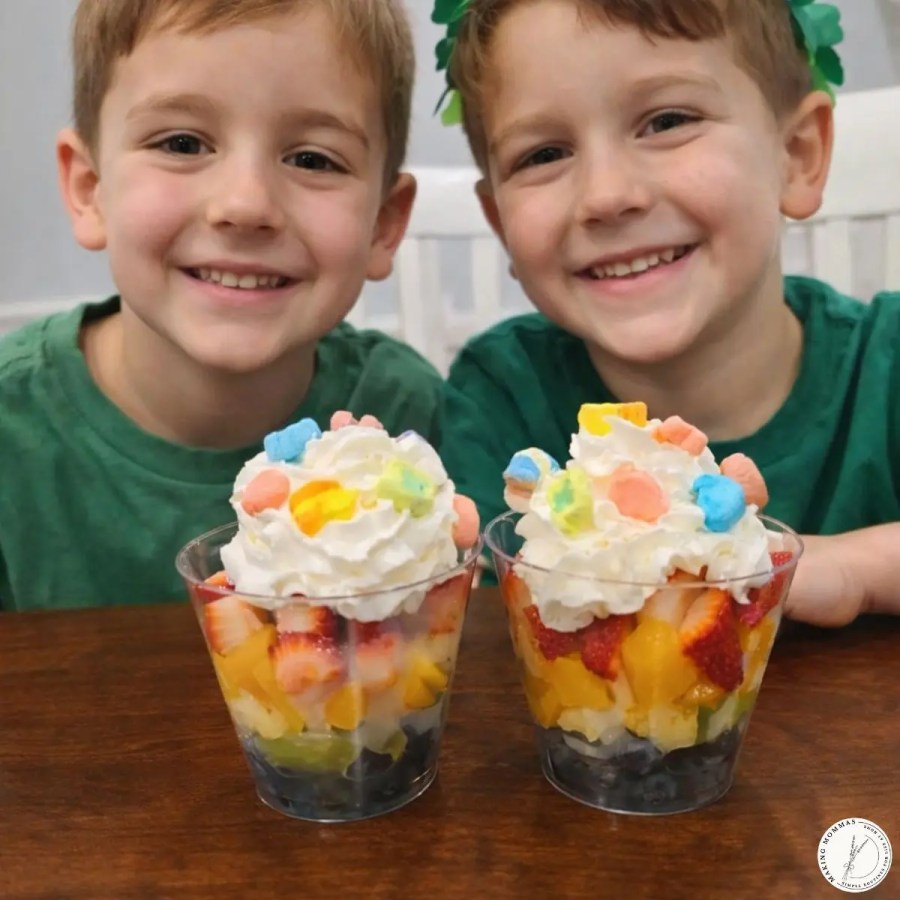 Rainbow fruit cups for St. Patrick’s Day with layers of fresh fruit, whipped cream, and colorful cereal marshmallows, served as a kid-friendly treat.