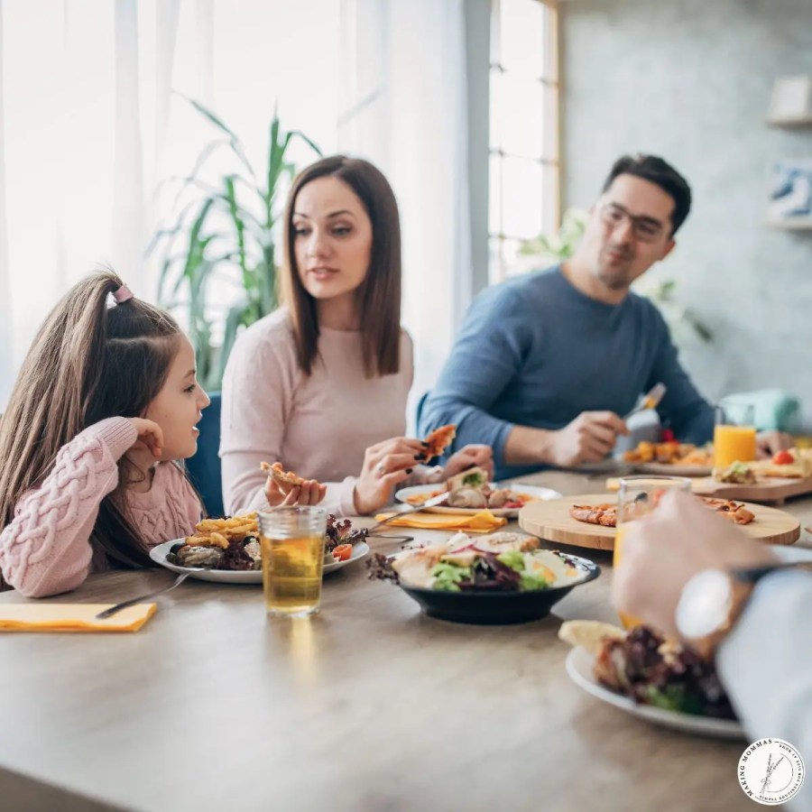 A family sitting together at the dinner table, sharing a meal and conversation, reflecting realistic expectations and everyday family life.