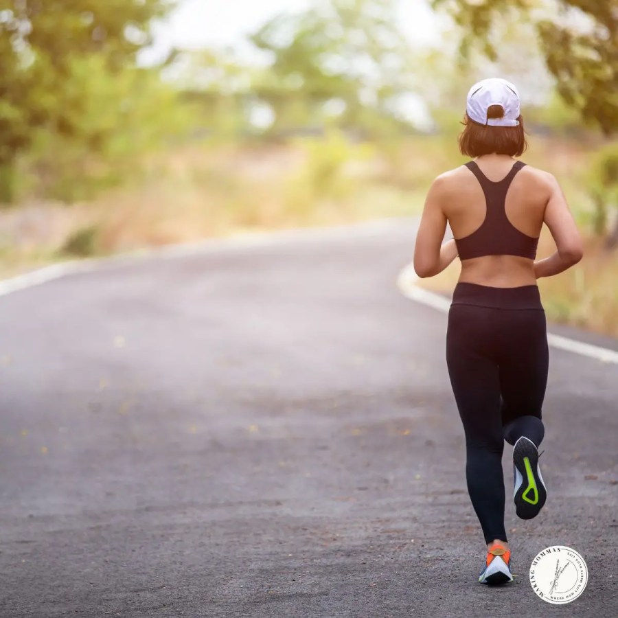 Woman jogging on a quiet road wearing a white reflective hat and athletic gear, a thoughtful Christmas gift idea for stay-at-home moms who enjoy early morning or evening runs.