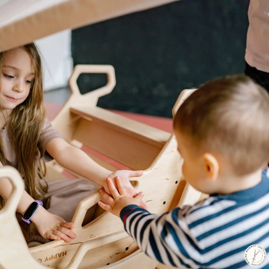 Two young children playing together indoors, gently holding hands and interacting, showing flexibility and connection during everyday play.