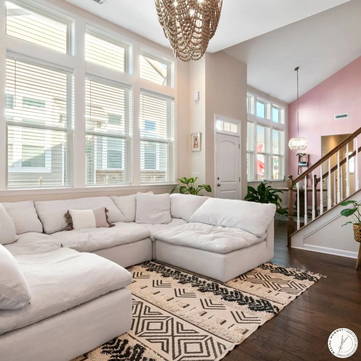 A bright, tidy living room with a clean sectional sofa, natural light, and plants, showing a calm home after completing a weekly home reset.