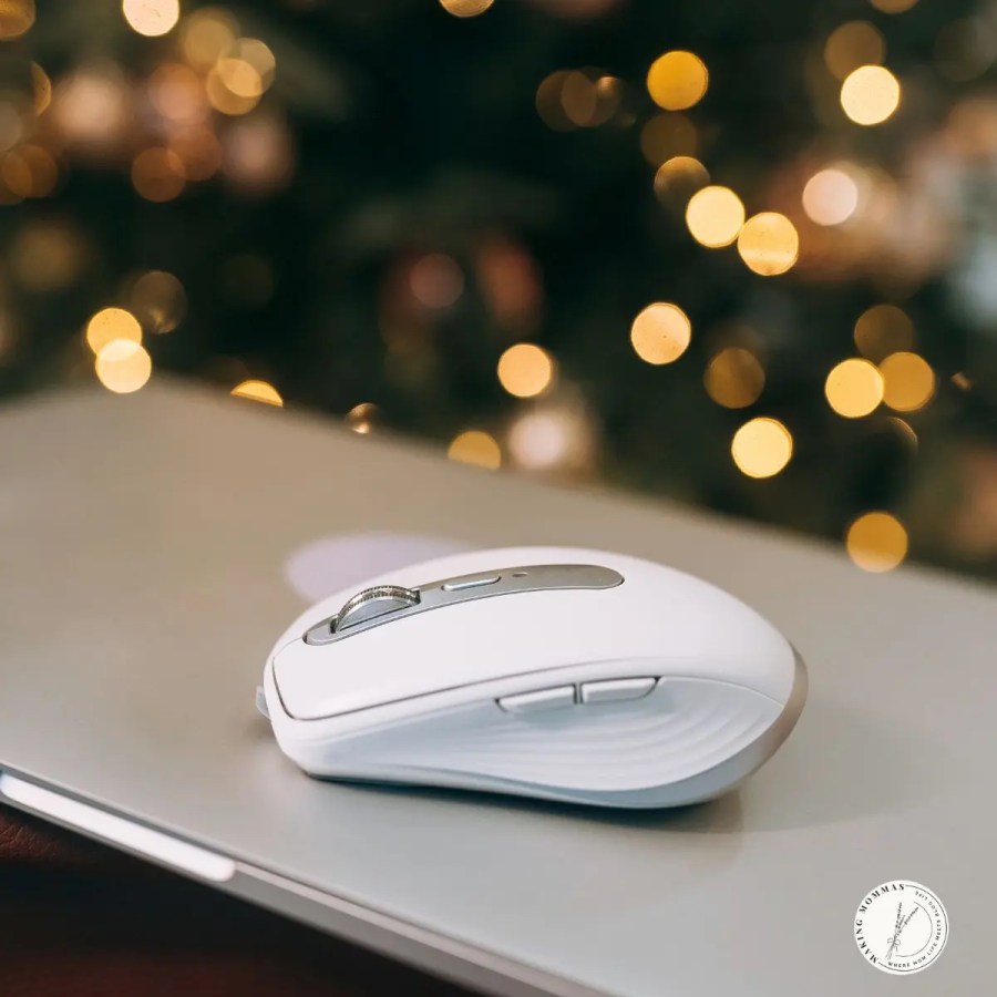 White wireless mouse on a laptop, sitting in front of a Christmas tree.